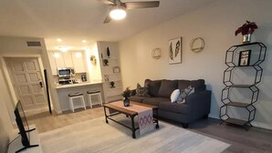 A living room with a grey sofa, a coffee table, a white rug, and a ceiling fan.
