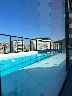 A rooftop pool with a clear view of surrounding buildings and a mountain in the distance. - Studio Go (Poços de Caldas)