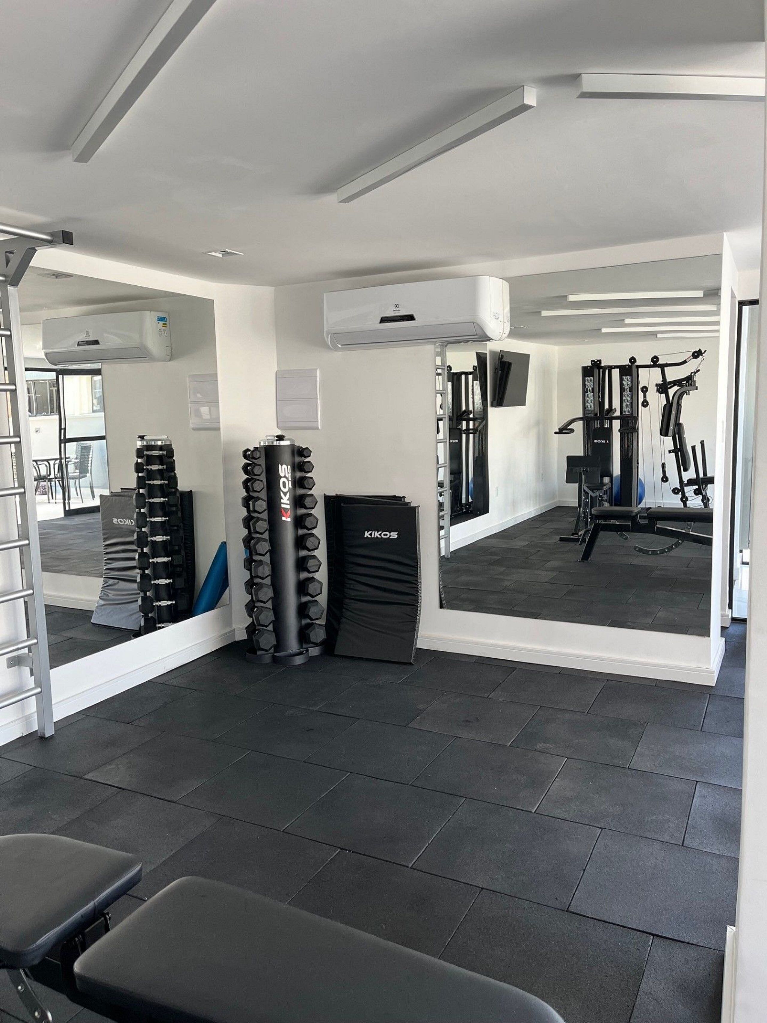 A gym with exercise equipment, a mirror, and a seating area.