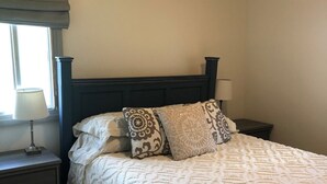 A neatly made bed with a patterned bedspread and pillows, a bedside table with a lamp, and a window with a view of the outdoors. - Charming farmhouse property on 20 acres of land, comfortably sleeps 13   (Lava Hot Springs)