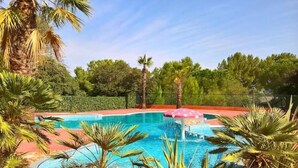 A swimming pool surrounded by palm trees and a red deck. - Logement Entier : Cabane - Agde, France (Agde)