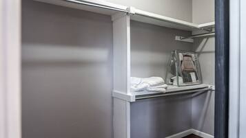 A walk-in closet with a white door, a hanging rod, and a shelf with folded clothes.