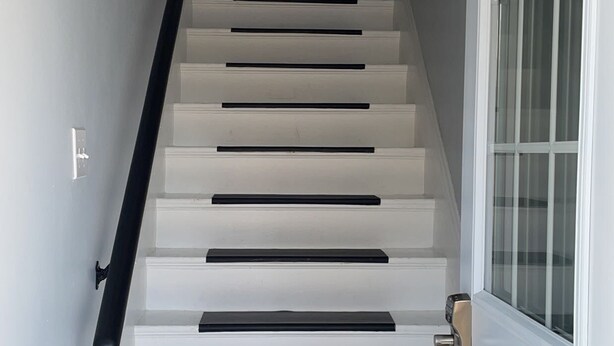 A staircase with white steps and black risers leading to a door with a glass panel. - Newly renovated 2 bedroom apartment  (Saint John)