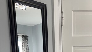 A bedroom with a large mirror, a bed, a nightstand, and a lamp. - Newly renovated 2 bedroom apartment  (Saint John)