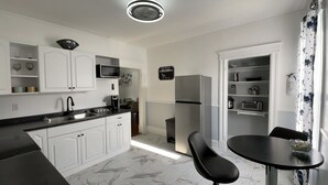 A modern kitchen with white cabinets, a black countertop, a built-in microwave, a refrigerator, and a dining area with a table and chairs. - Newly renovated 2 bedroom apartment  (Saint John)
