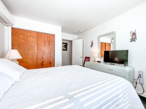 Ein Hotelzimmer mit einem großen Bett, einem Fernseher, einem Schminktisch und einem Kleiderschrank.