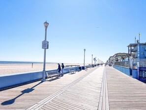 Una passerella di legno con panchine e lampioni che conduce a una spiaggia.