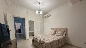 Een slaapkamer met een bed, een televisie en een kledingkast.