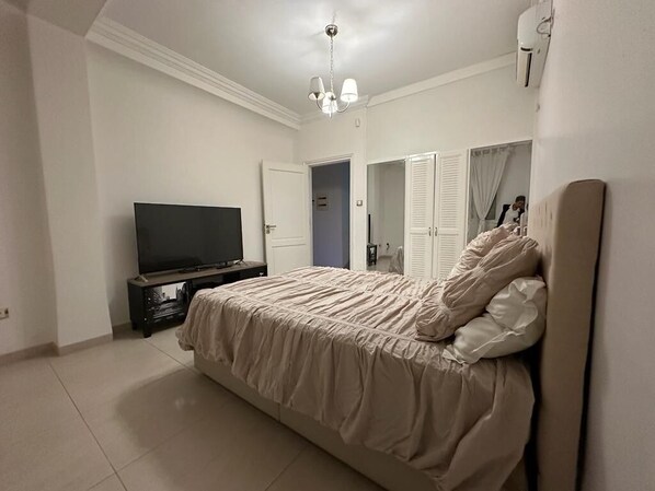 Un dormitorio con cama, televisor, armario y espejo.