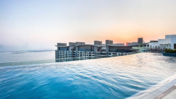 A modern infinity pool with a view of the city skyline at sunset. - Modern studio on Palm Jumeirah (Dubai)