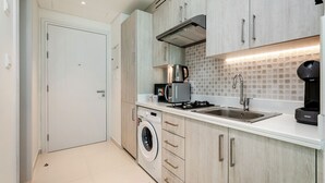 A modern kitchen with a washing machine, a coffee maker, and a sink. - Modern studio on Palm Jumeirah (Dubai)