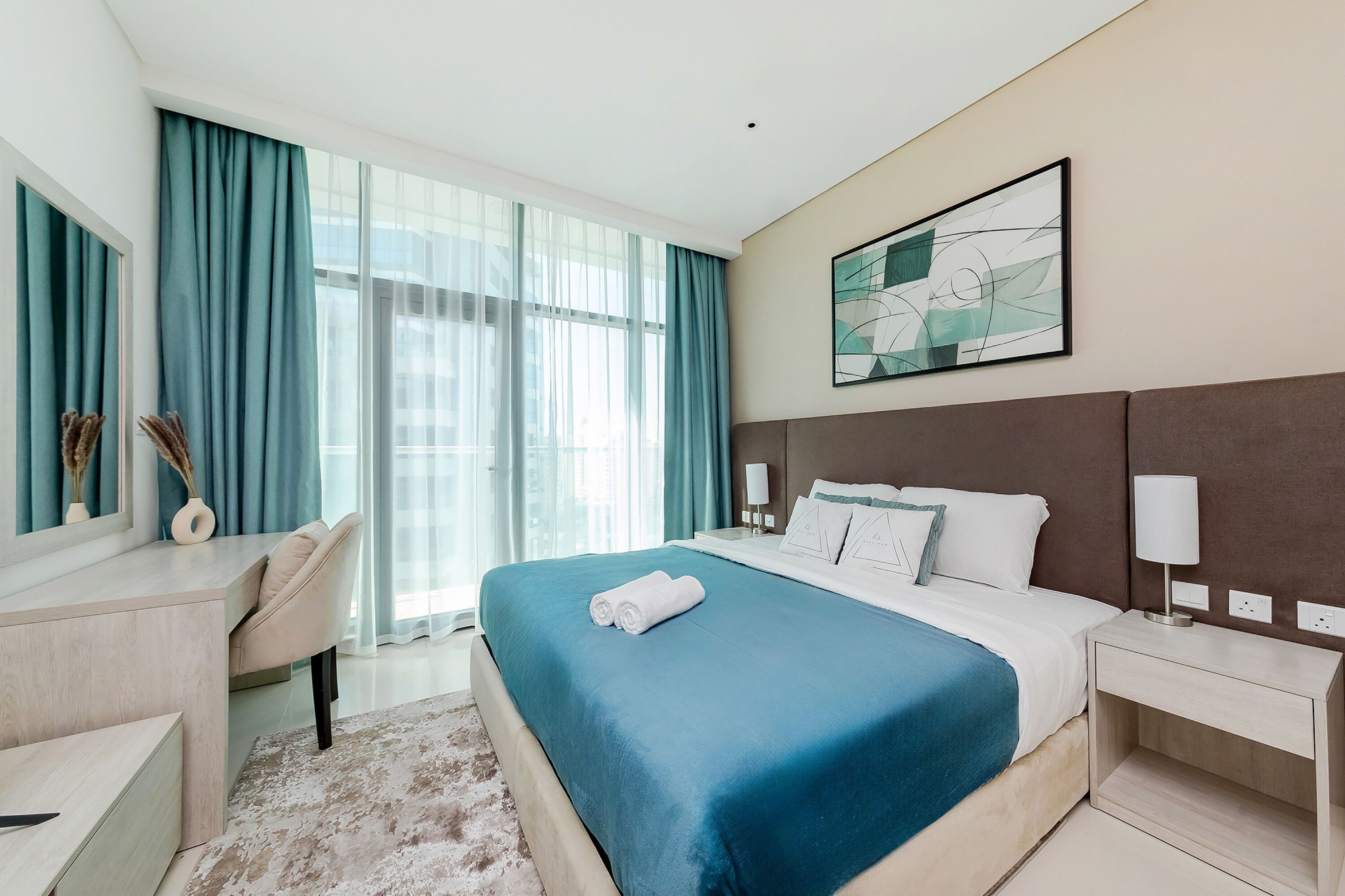 Une chambre d’hôtel moderne avec un grand lit, un bureau et une fenêtre avec des rideaux.