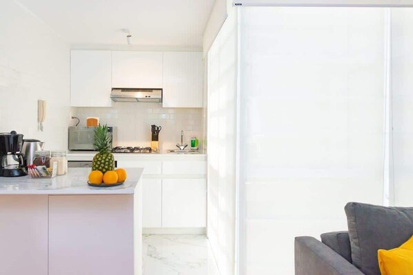 Une cuisine moderne avec des meubles blancs, un four à micro-ondes, une cuisinière et une machine à café.