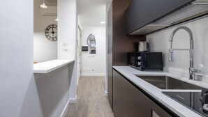 Et moderne køkken med en stålvask, en mikroovn og en elkedel på bordet.