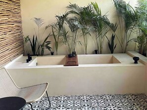 A bathroom with a bathtub, a chair, and various plants. - Nature Retreat: Tulum Apartment with Tub & Terrace (Tulum)
