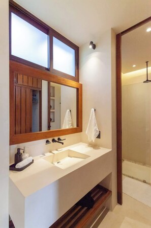 A modern bathroom with a large mirror, two sinks, and a shower.