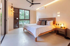 A bedroom with a bed, bedside table, and a ceiling fan.