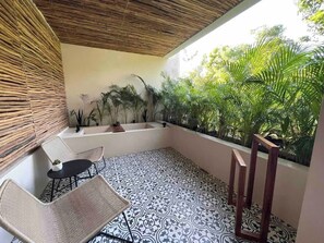 A balcony with a patterned floor, wicker furniture, and potted plants.