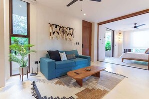 A modern living room with a blue sofa, a coffee table, and a large window.