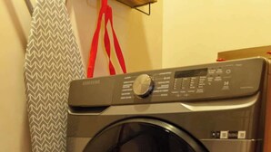 A front-loading washing machine in a laundry room with a patterned towel hanging on a rack.