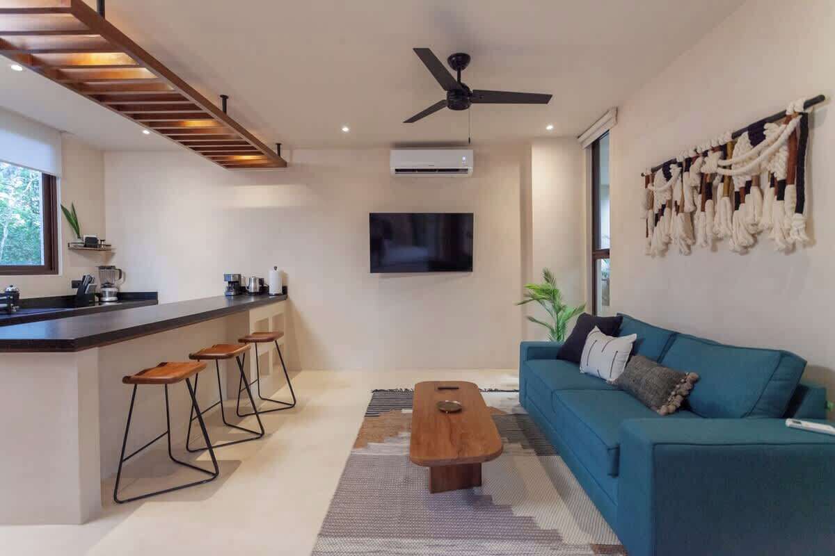 A modern living room with a sofa, a coffee table, and a bar area with stools.