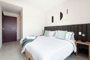 A bedroom with a bed, bedside tables, a door, and wall-mounted artwork. - Beautiful design in Polanco, 2 rooms (Ciudad de México)