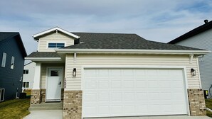 Une maison de plain-pied avec une porte de garage blanche, une porte d’entrée et un petit porche.