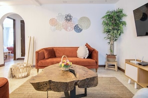 Una sala de estar con un sofá, una mesa de centro, una planta y decoración en la pared.