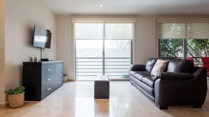 A modern living room with a sofa, a TV, a cabinet, and a sliding glass door.