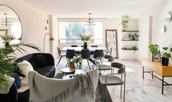 Una sala moderna con sofá, sillas, una mesa de comedor y plantas en macetas.