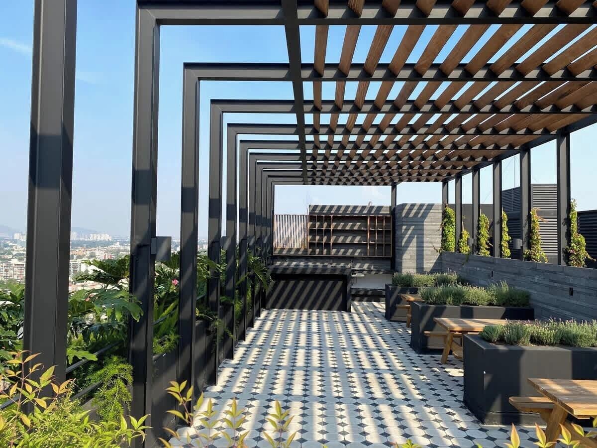 Une terrasse sur le toit dotée d’un sol à motifs, d’une pergola en bois et d’espaces aménagés pour s’asseoir.