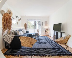 Una sala de estar moderna con un sofá, dos sillones, una mesa de centro y un televisor.