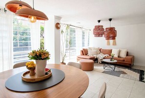 A modern living room with a round wooden dining table, a sofa, and a coffee table.