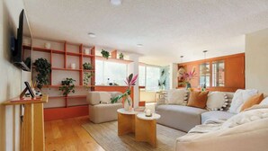 Een woonkamer met twee banken, een bijzettafeltje en planten op planken.