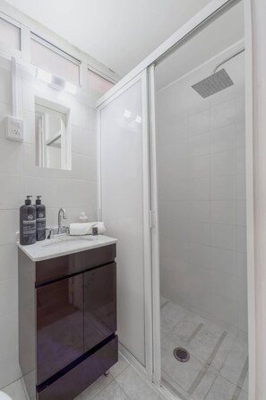 Une salle de bain moderne avec une douche à parois de verre, un lavabo avec un miroir et des articles de toilette.