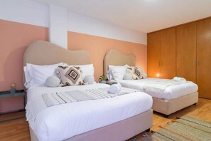 Une chambre d’hôtel avec deux lits, une armoire, une table de chevet et une petite plante.