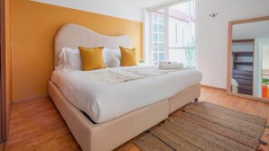 Een slaapkamer met een bed, een raam en uitzicht op een trap.