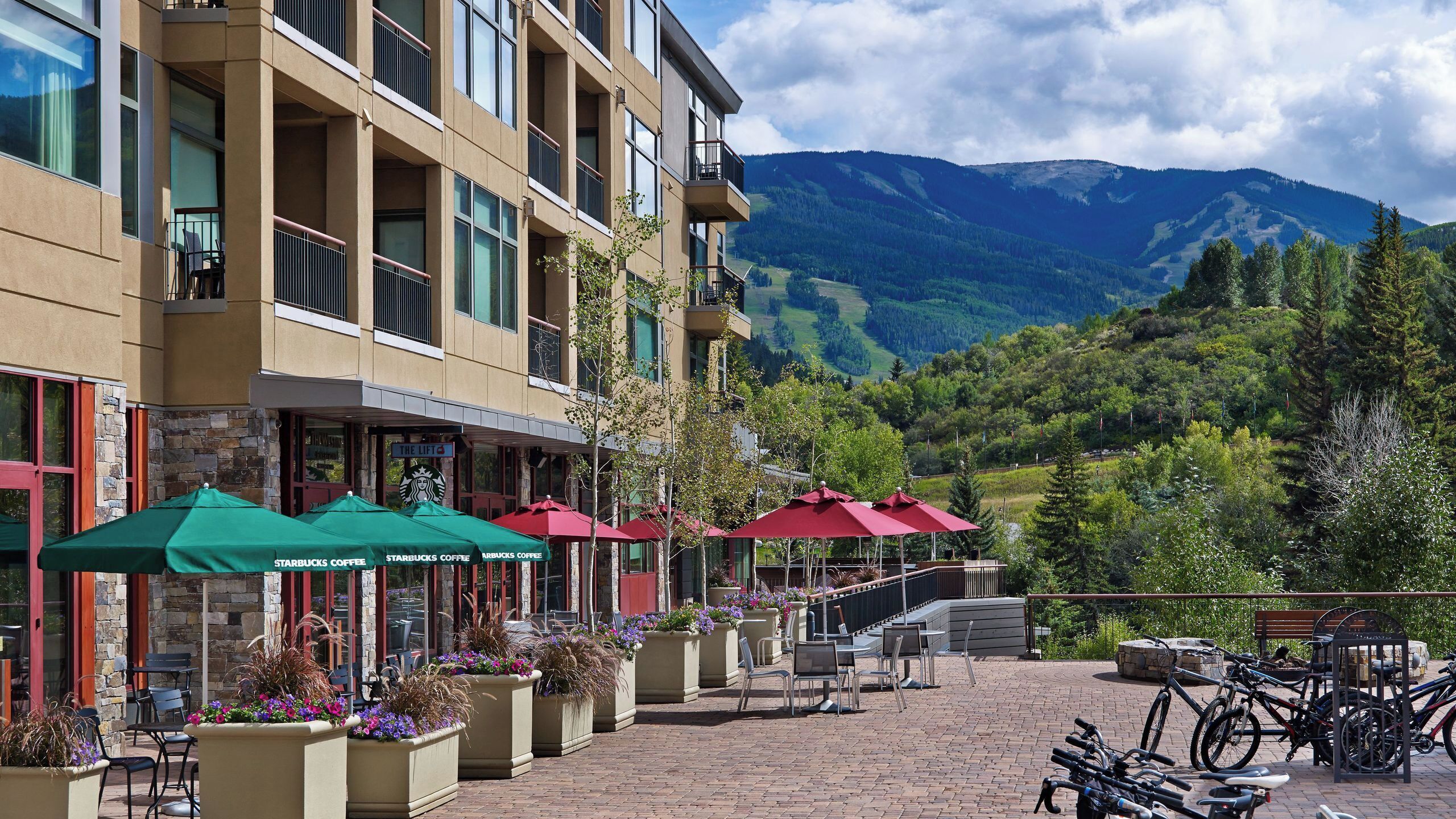 A multi-story hotel with outdoor seating, a Starbucks coffee shop, and mountain views.
