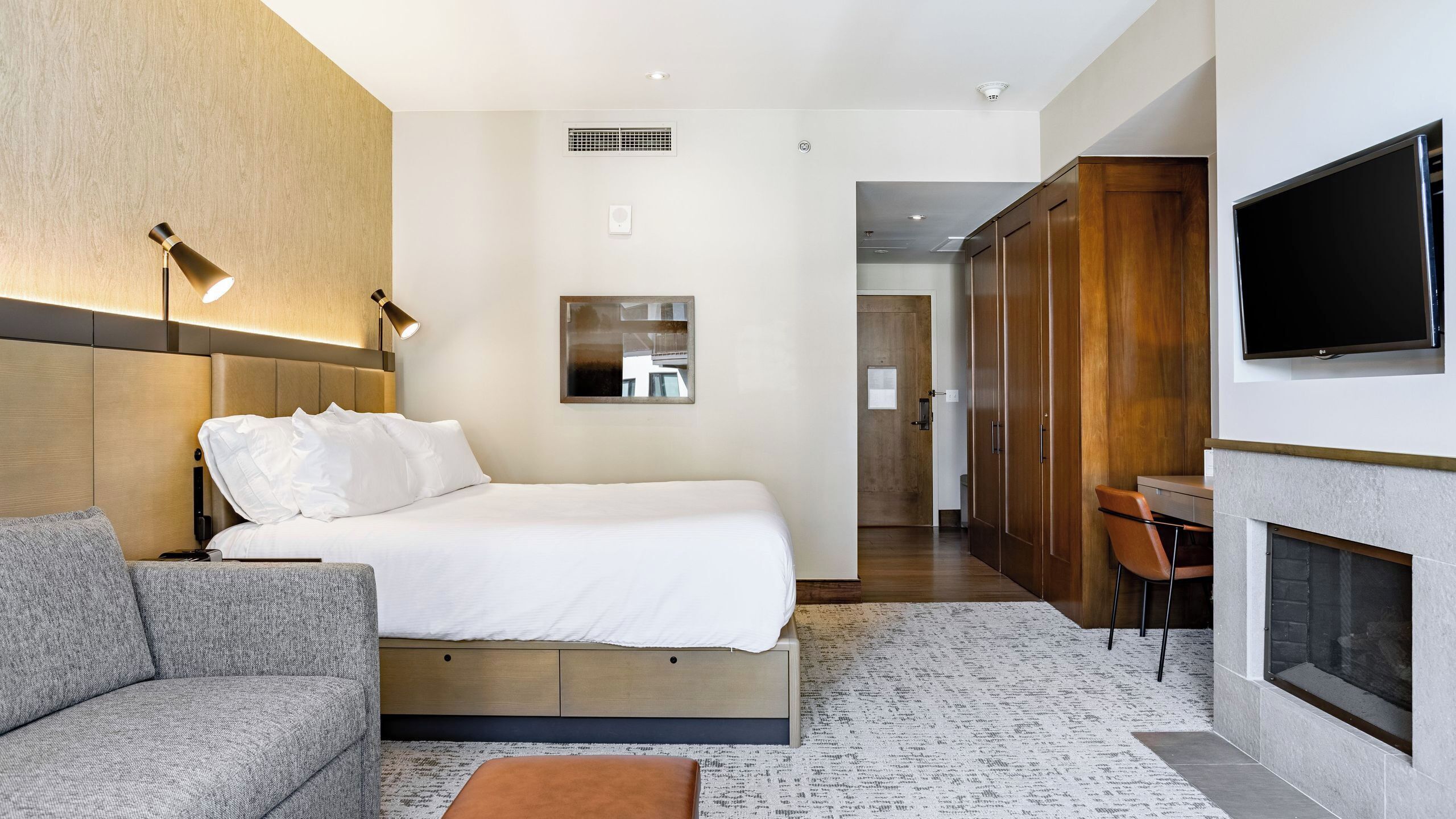 Une chambre d’hôtel moderne équipée d’un lit, d’un canapé, d’une télévision et d’une cheminée.