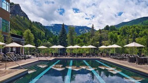 A swimming pool with lounge chairs and umbrellas, surrounded by mountains and trees. - Eagle River by Avantstay Located in the Westin (Avon)