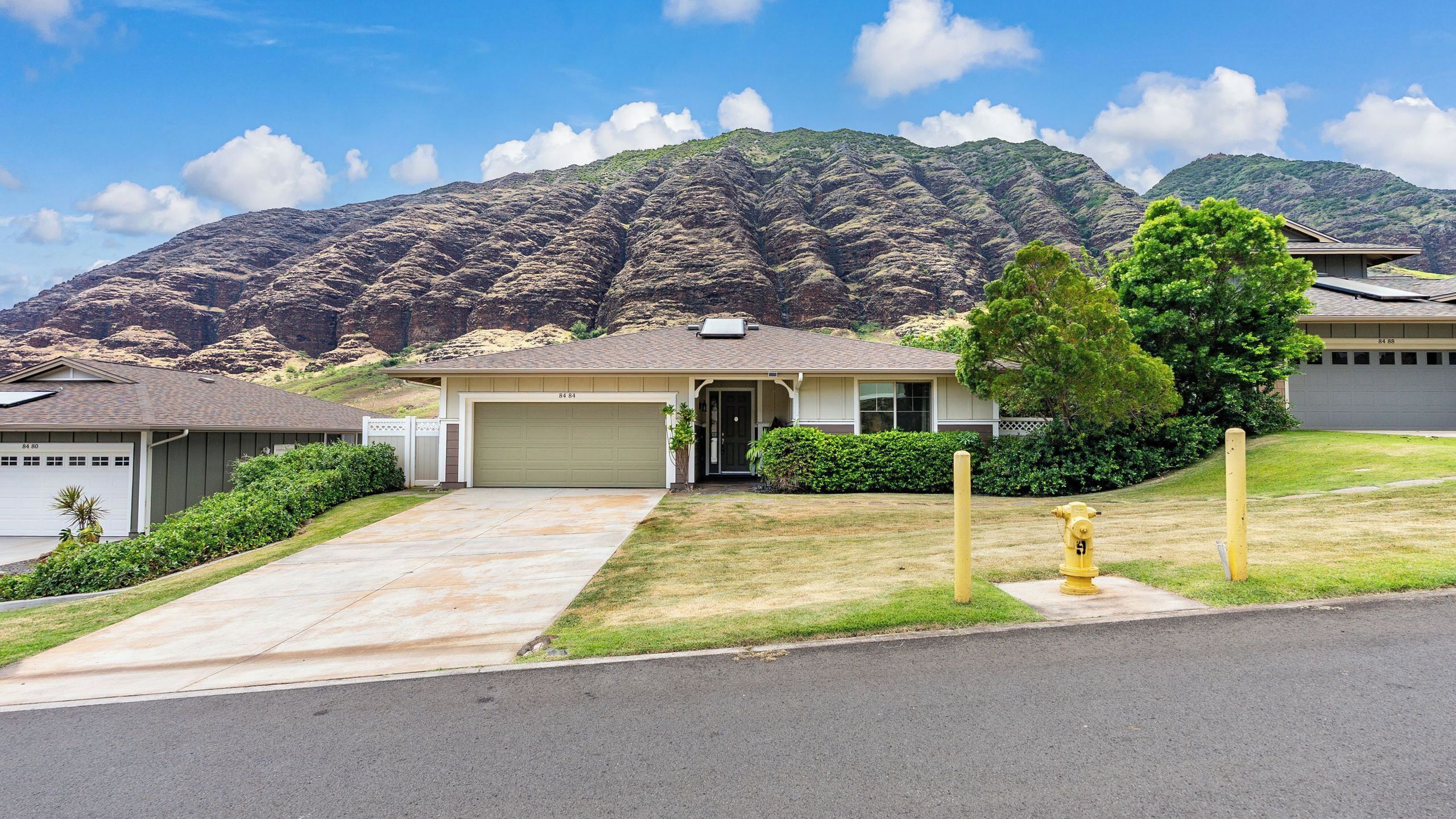 A single-story house with a garage, a front yard, and a mountain backdrop.