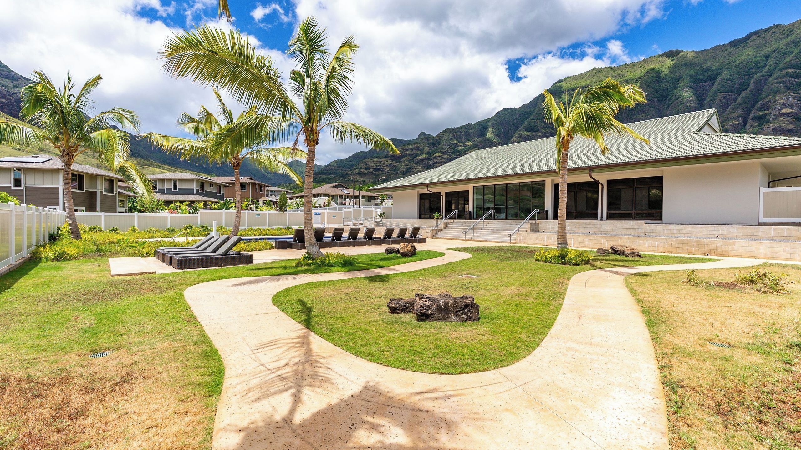 A resort with a pool area, lounge chairs, and a view of mountains.