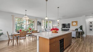 A modern kitchen with a central island, wooden chairs, and a dining table. - Pakele Oahu by Avantstay 5 Min to Makaha Beach (Waianae)