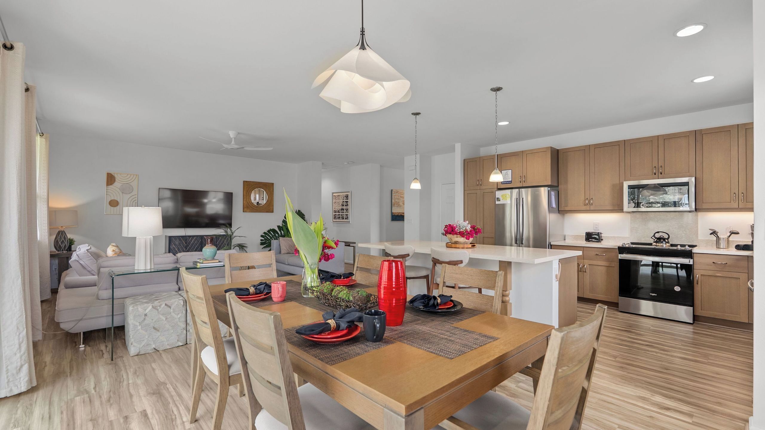 Une cuisine moderne avec des meubles en bois, des appareils en acier inoxydable et un coin repas comprenant une table et des chaises en bois.
