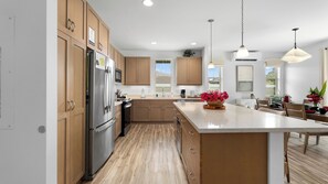 Une cuisine moderne avec des meubles en bois, des appareils en acier inoxydable et un grand îlot central agrémenté d’un vase de fleurs.