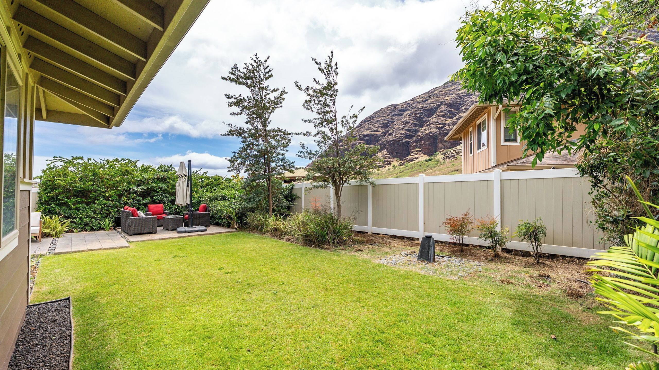 Un jardin avec une pelouse, du mobilier d’extérieur, une terrasse en bois et une montagne en arrière-plan.