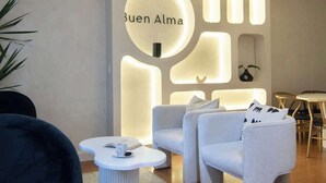 Ein modernes Wohnzimmer mit einer Sofagarnitur, einem Couchtisch und einer wandmontierten Leuchte mit dem Schriftzug "Buen Alma".
