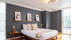 A bedroom with a large bed, a wooden floor, a dark wall, and three framed artworks above the bed. - KOKU! Best location in Polanco 10 guests (Ciudad de México)