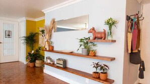 A hallway with wooden floors, a white door, and a wall with shelves holding plants and a small dog figurine. - KOKU! Best location in Polanco 10 guests (Ciudad de México)