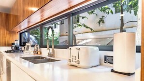 A modern kitchen with a large window, a toaster, and a sink. - Stunning modern villa with pool & beach access (Playa del Carmen)